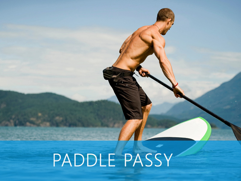 Participants en paddle sur une rivière calme, entourés de montagnes majestueuses.